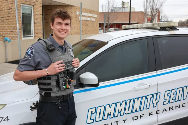 unk student Zach Arner stands in front of a police car