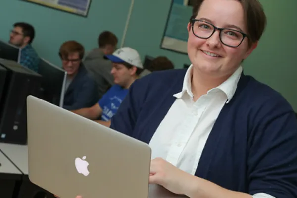 a student sits in a classroom with a laptop