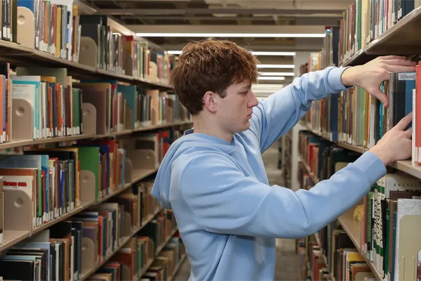 a student places books on a library shelf