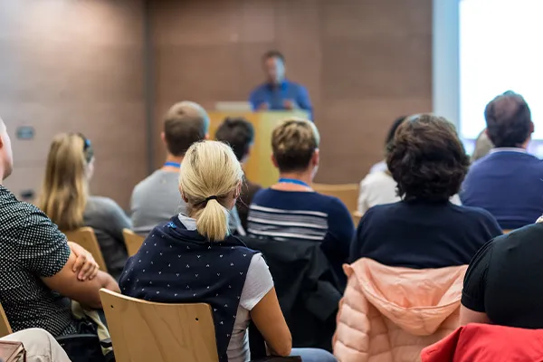 a crowd listens to a speaker at a public meeting