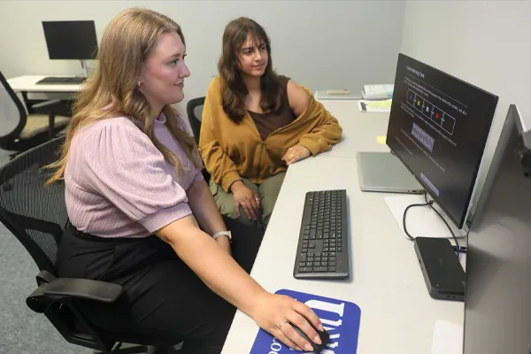 a student and instructor examine readouts on a computer screen