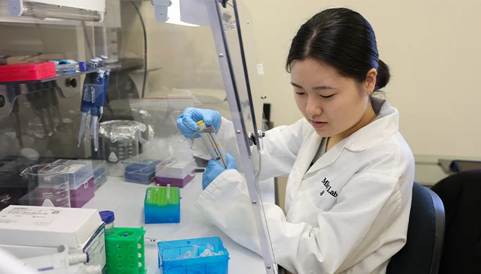 a faculty member works on research in a science lab