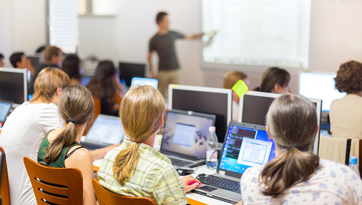 Students sit in front of their laptops during a lecture