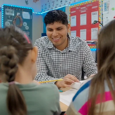 a teacher sits at a table with students