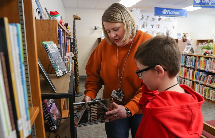 a teacher picks out a book with a student