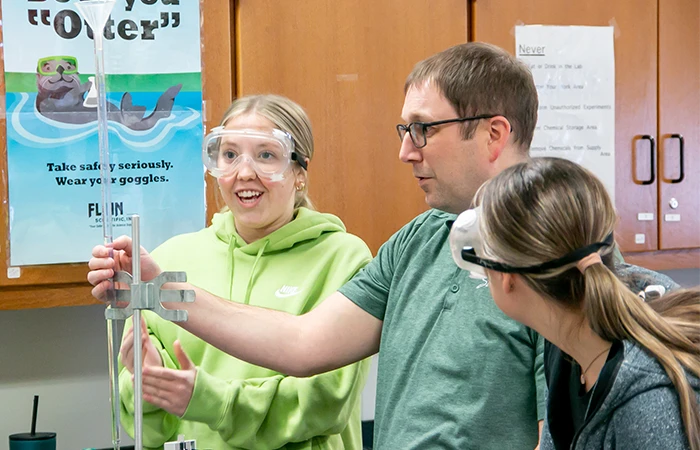 an instructor works with students in a science lab classroom