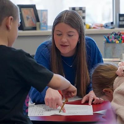 a teacher works with a young student at a table