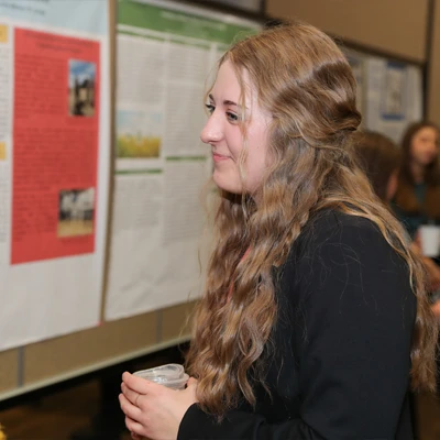 a student stands in front of a poster during a presentation 