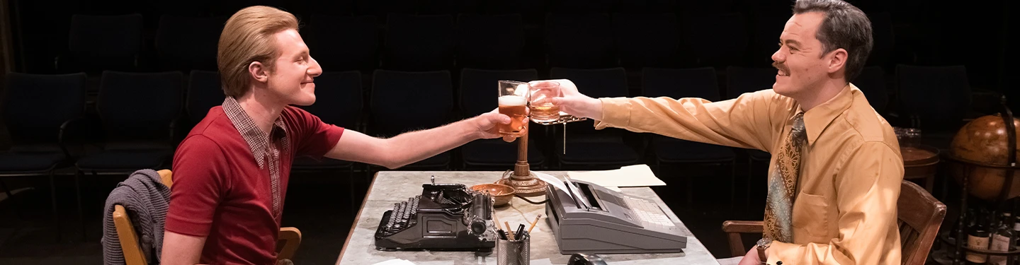 two students toast over a desk during a play