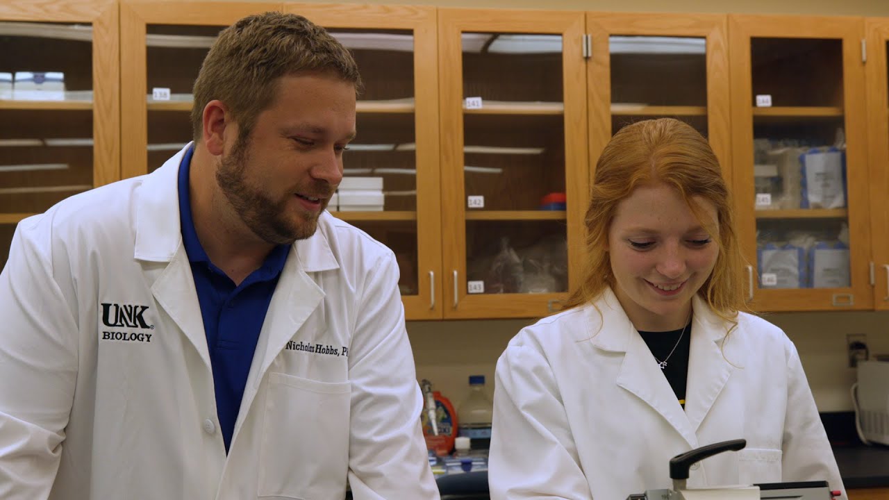 a student and professor wearing labcoats