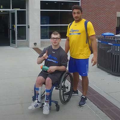 a student stands next to a student using a wheelchair throwing the lopes