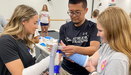two students work with an instructor at a summer camp
