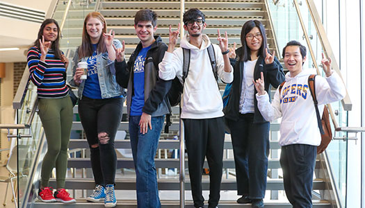 smiling students pose on the stairs