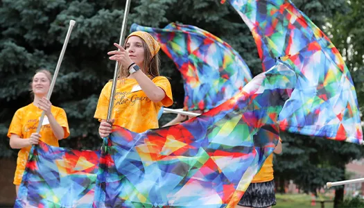 student twirl flags at a marching band camp