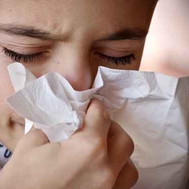 person sneezing with tissue on nose