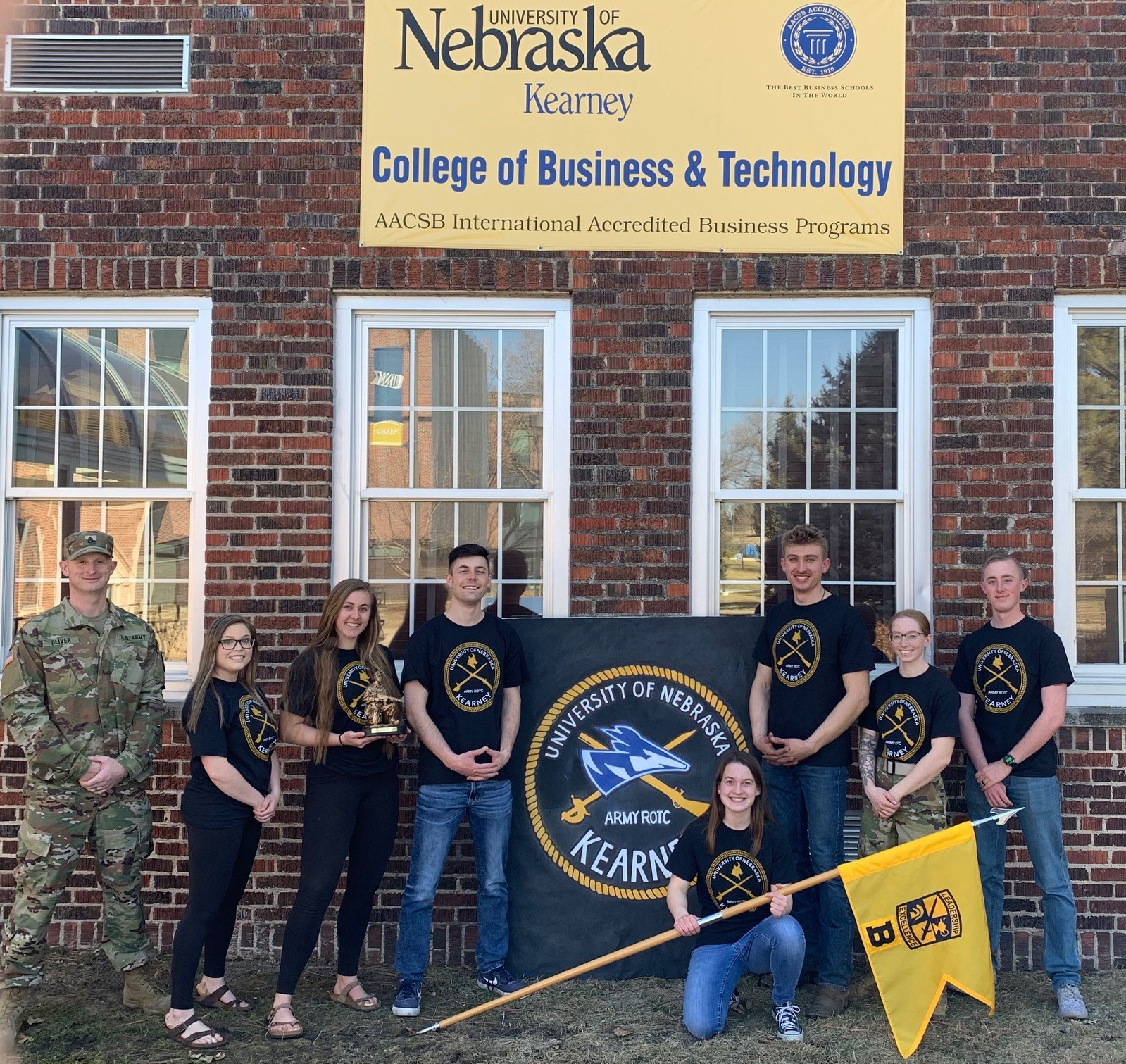 UNK ROTC posing with rotc banner in front of West Center