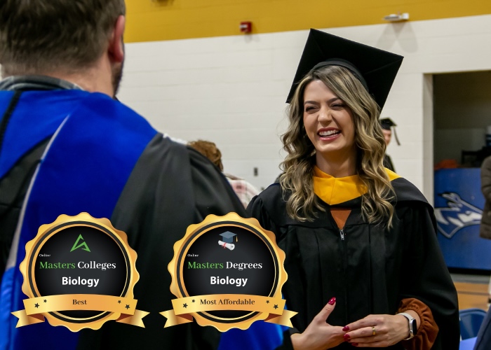 Woman in cap and gown talking with professor.