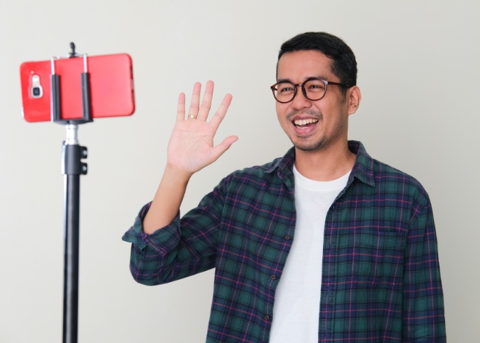 Man waving at video call on his phone.