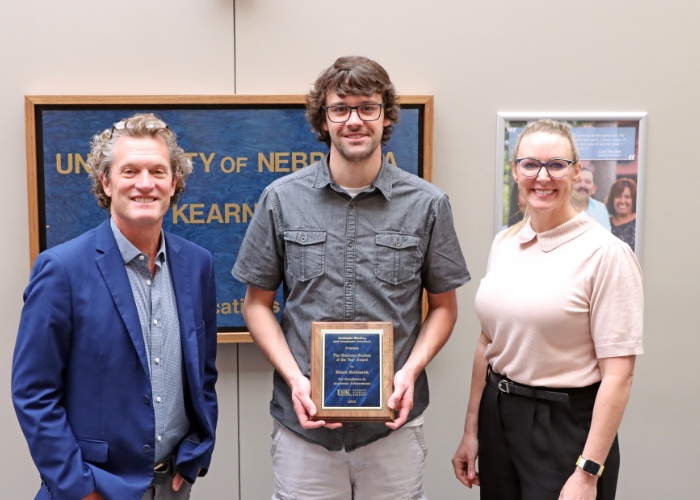 Three people posing with award.