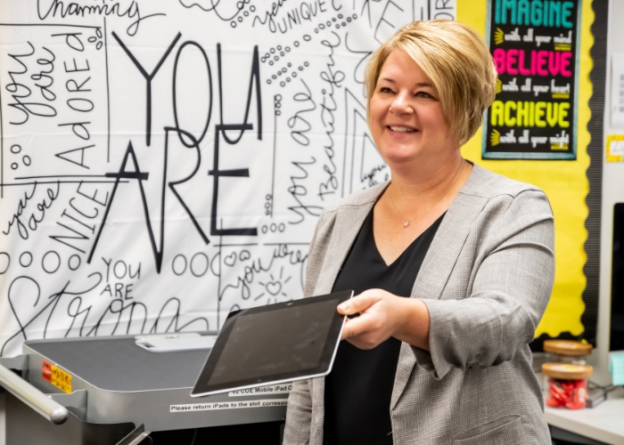 Woman handing Ipad to someone.