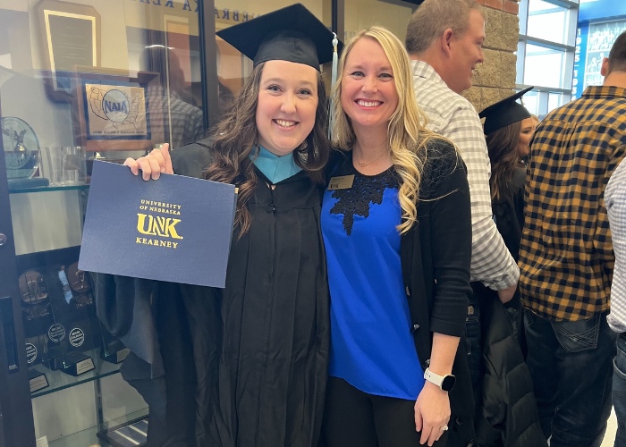 Graduate posing with degree and woman.