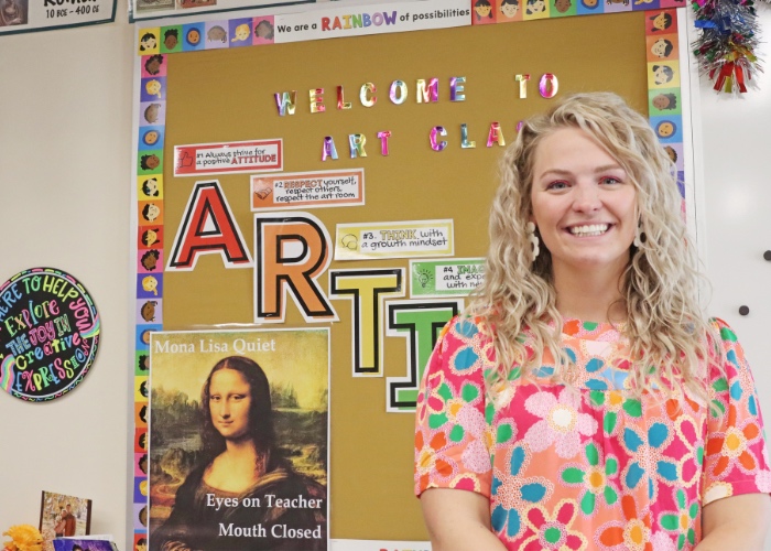 Woman standing in front of teacher bulletin board.