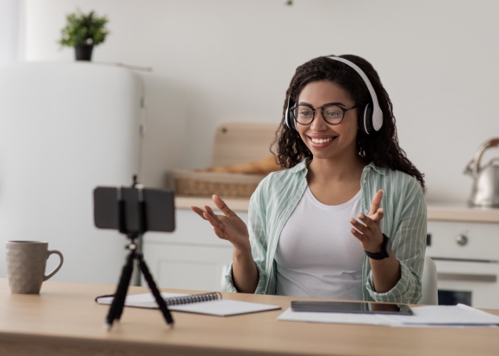 Woman recording video on cell phone at a desk.