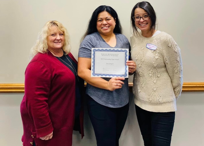 Woman with certificate standing between two professors.