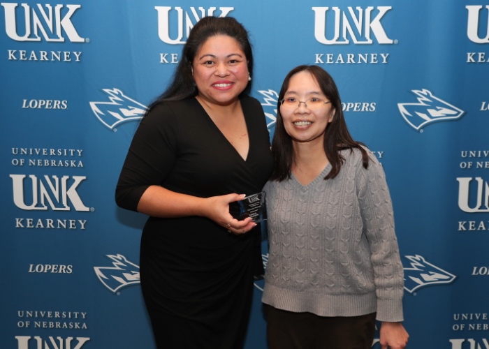 Two women smiling in front of photo backdrop.