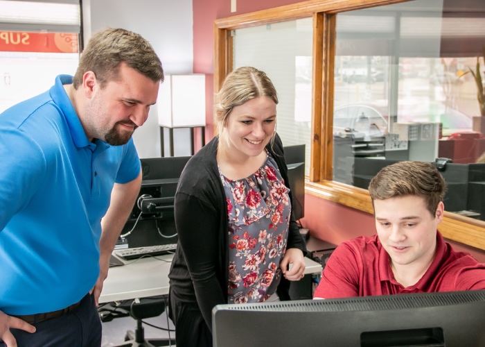 Three people looking at computer screen.