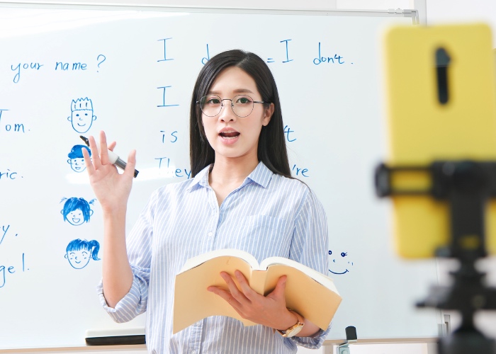 Woman recording lecture with cellphone.