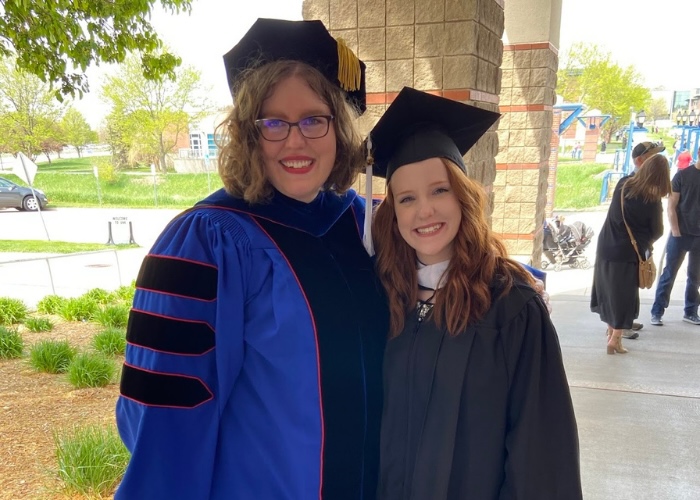 Professor and graduate student smiling in graduation attire.