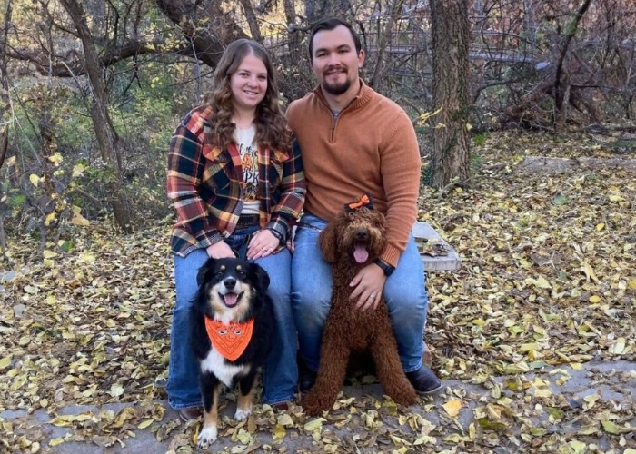 Payton sitting on bench with wife and two dogs.