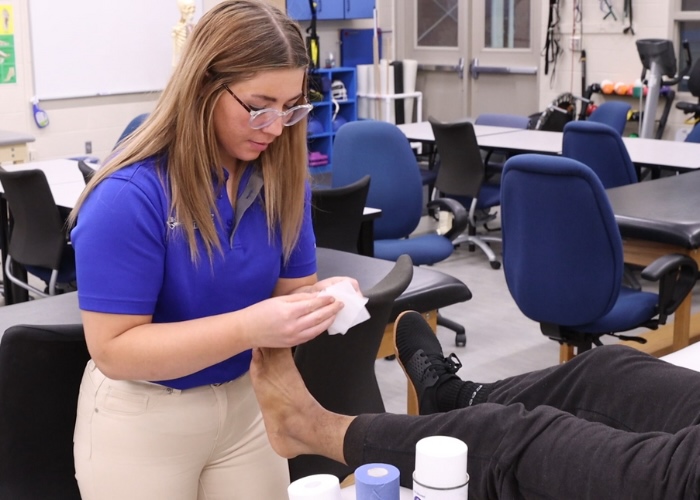 Woman wrapping an athletes ankle.
