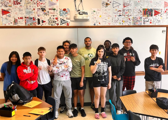 Teacher and students standing at the front of the classroom.