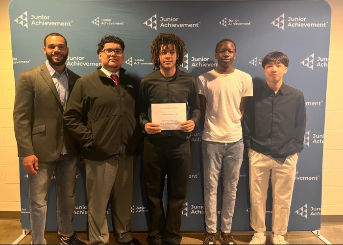 Teacher with four students holding award.