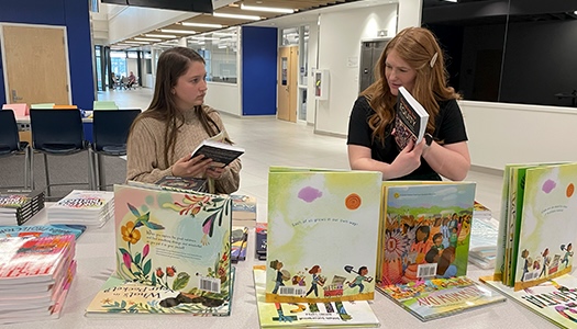 Two female teachers skimming through free books at UNK's event.