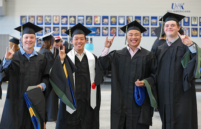Four MAT graduates in their caps and gowns at UNK's graduation.