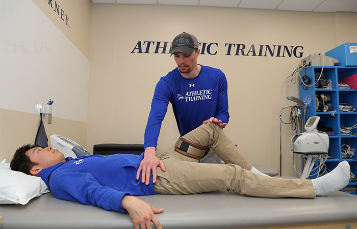 UNK Athletic Training student working on a person lying on their back.