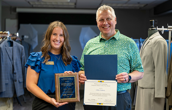 Chloe Dakan and College of Business and Technology Dean Dr. Jares holding her Graduate Student of the Year award and smiling at the camera.
