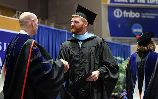 A UNK graduate student shakes UNK Chancellor Dr. Neal Schnoor's hand at UNK's commencement ceremony.