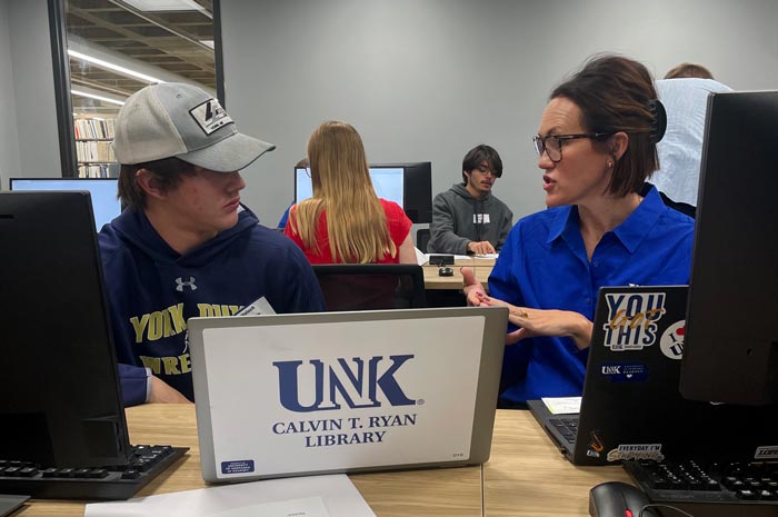 Student and instructor talk at a computer workstation in the UNK Calvin T. Ryan Library.