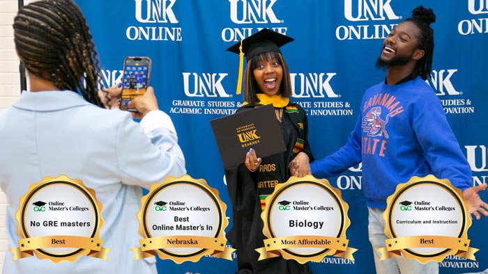 Woman wearing UNK graduation regalia holding hands and posing with a man in front of a UNK photo backdrop. Four badges are at the bottom of the image.