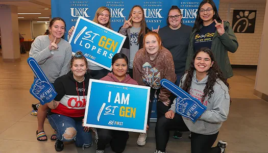 a group of students post with a sign that reads first gen