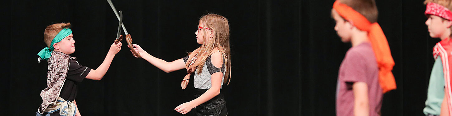 students dressed in costume fight with wooden swords