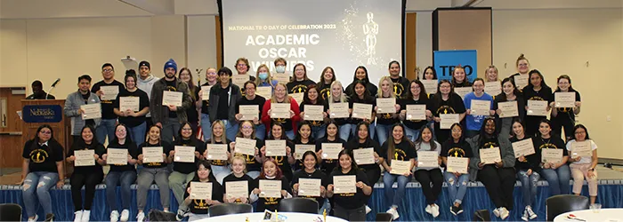 a large group of students pose together holding up certificates