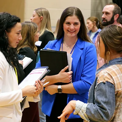 a student holding a binder smiles during the career fair event