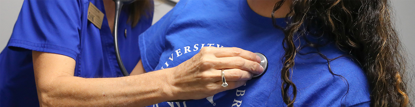 Nurse checking students heart beat with stethoscope