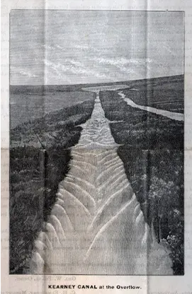 Black-and-white photo of the Kearney Canal at the overflow, showing a long, straight waterway stretching into the distance.