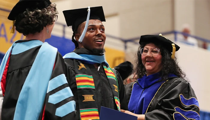 a student with professors at commencement
